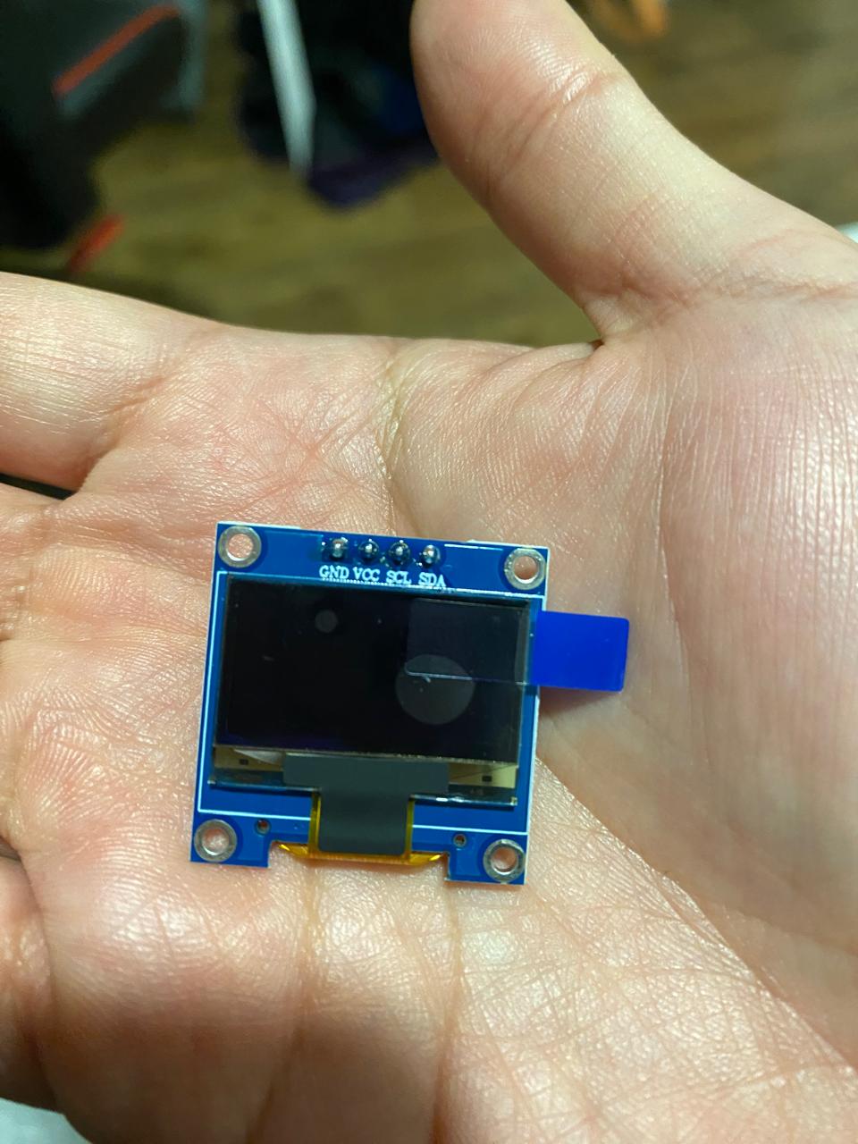 Pequeña pantalla OLED sostenida en una mano.
